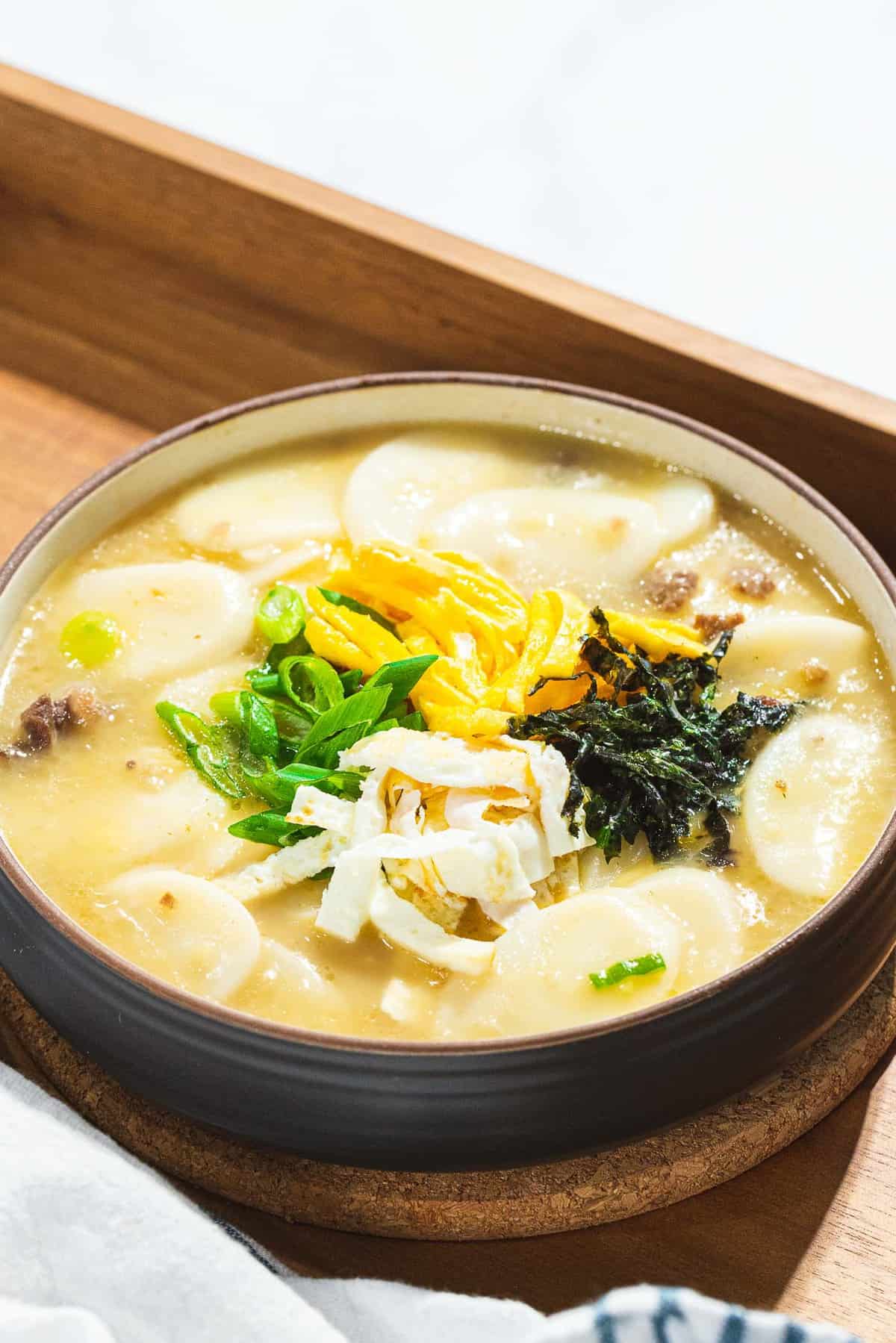 Tteokguk or Korean rice cake soup garnished with eggs, seaweed, and scallions.