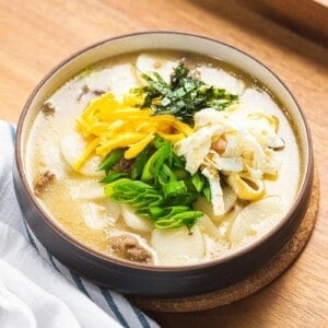 Tteokguk or Korean rice cake soup in beef broth garnished with eggs, seaweed, and green onions.