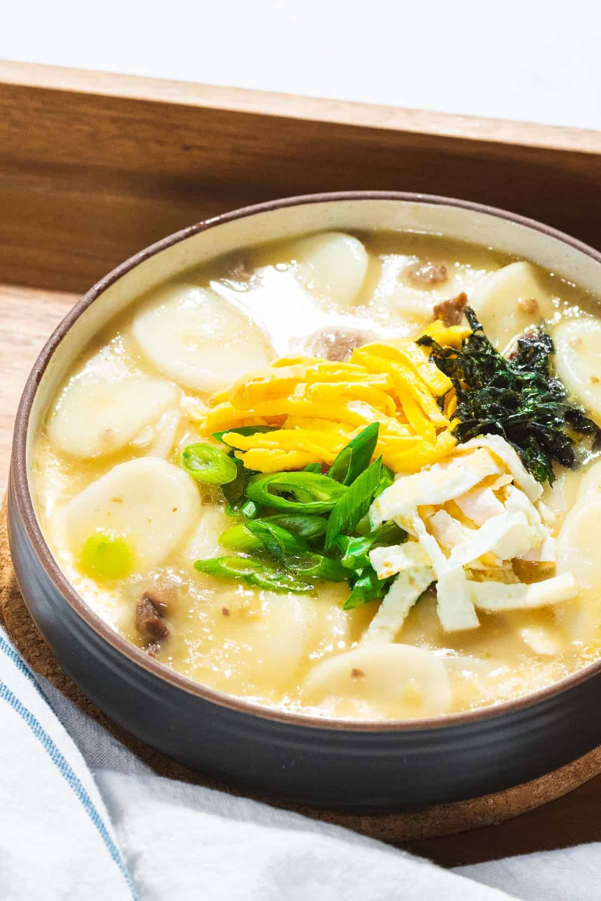 Tteokguk made with Korean rice cakes and beef broth garnished with eggs, gim, and scallions.