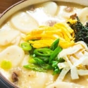 Tteokguk or Korean rice cake soup with text overlay.