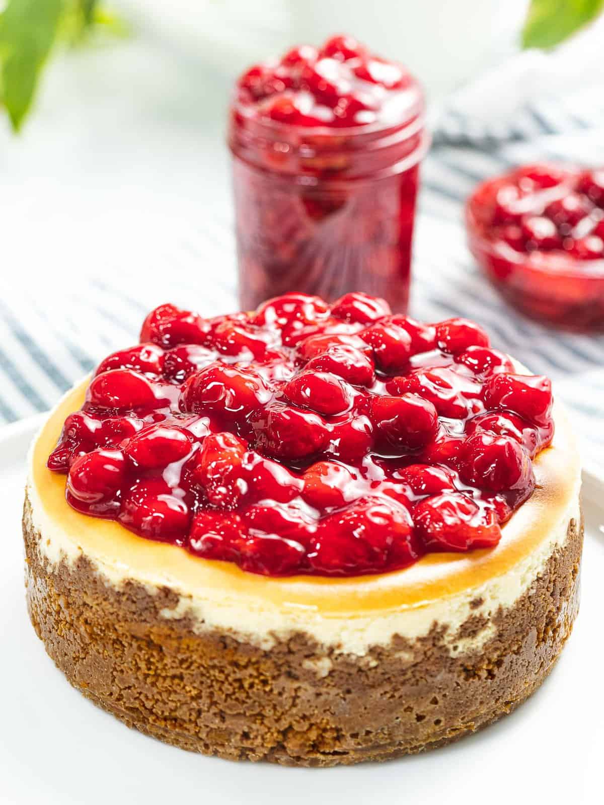 Cherry cheesecake next to a jar of cherry topping.