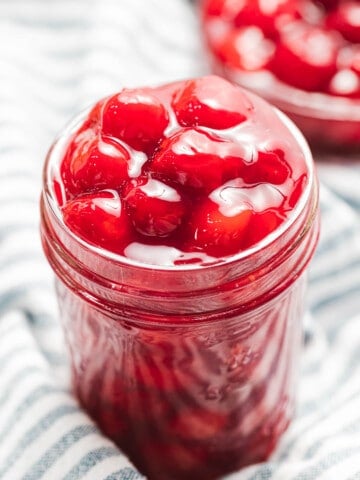 Cherry pie filling with red cherries in a glass mason jar.