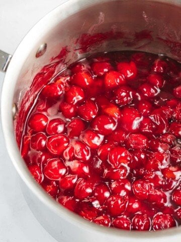 Cherry sauce cooked until bright red and glossy in a pan.