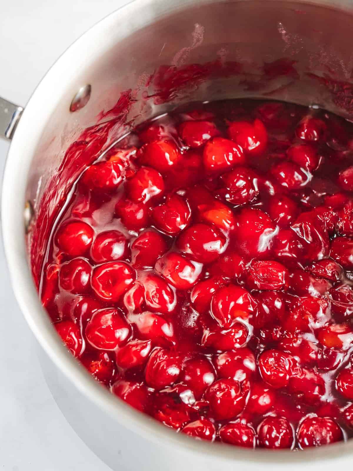 Cherry topping cooked until bright red and glossy in a pan.
