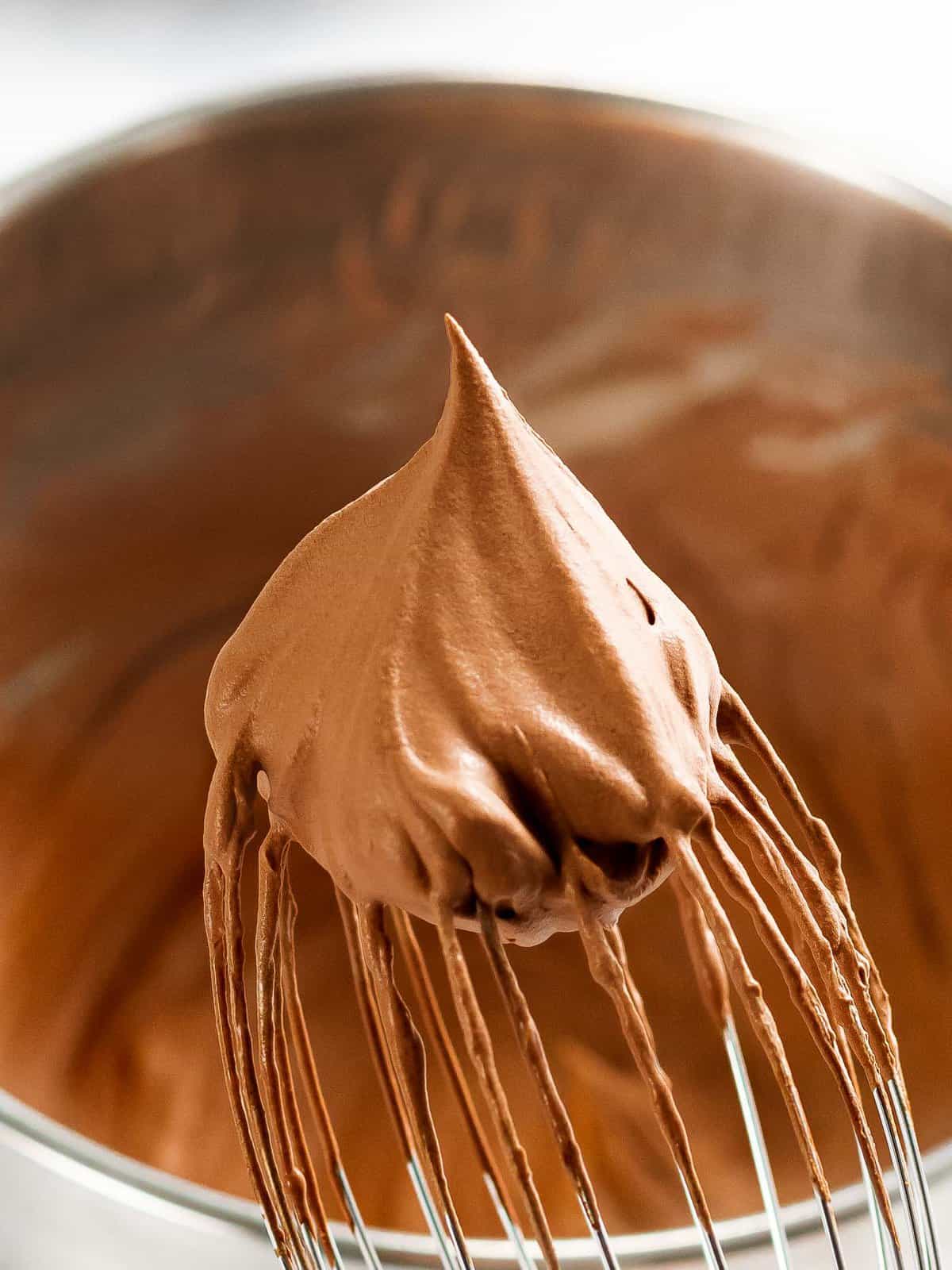 Fluffy homemade chocolate whipped cream on the end of a whisk.