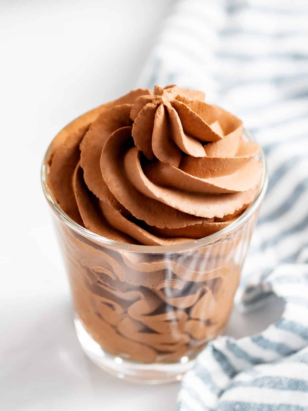 Chocolate whipped cream piped into a glass cup.
