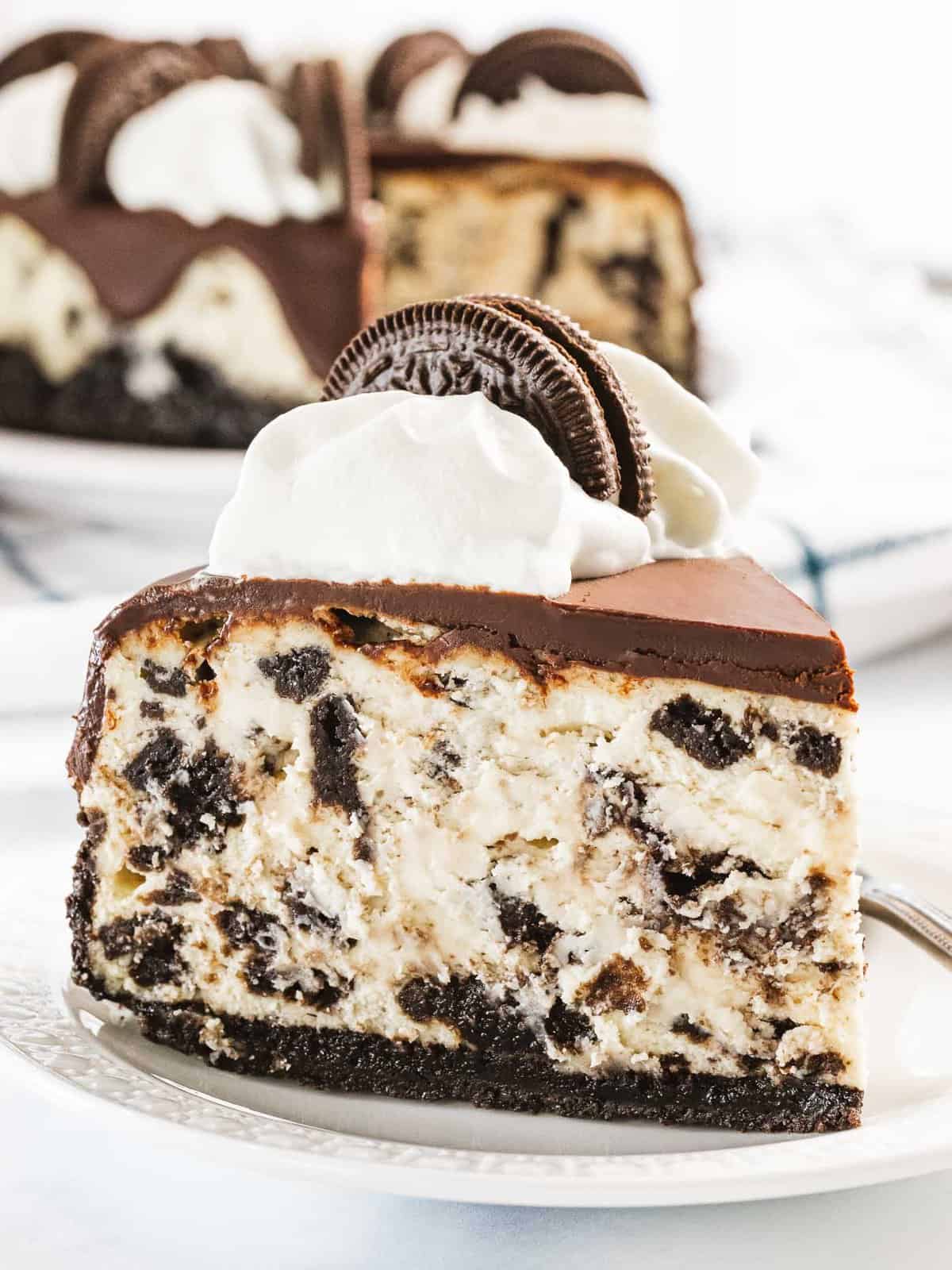 A slice of Oreo cheesecake with chocolate ganache and whipped cream.
