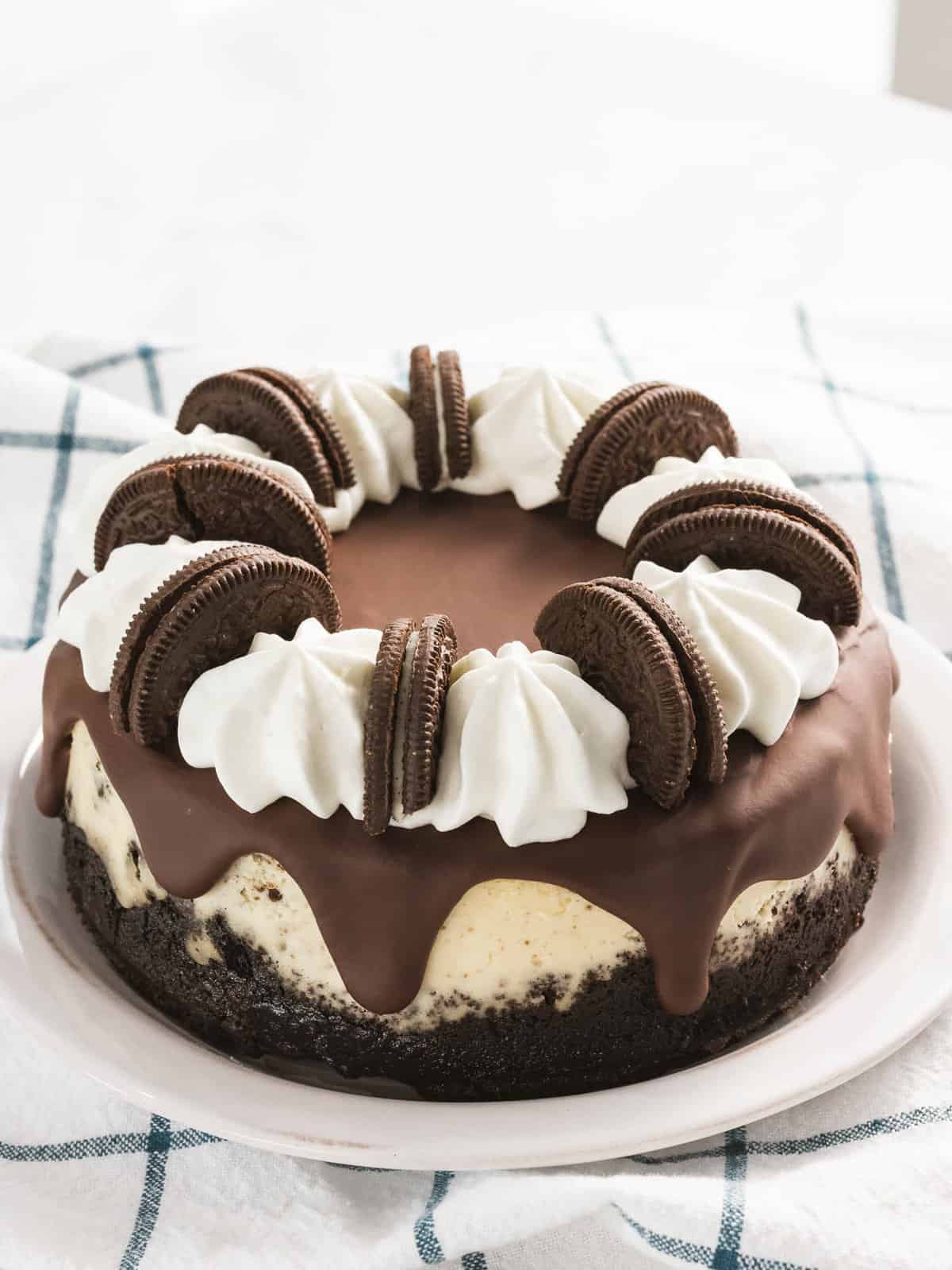 Oreo cheesecake decorated with Oreo cookies, whipped cream, and ganache.