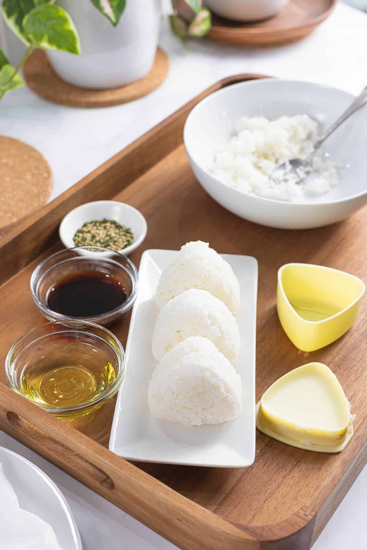 Rice balls formed into triangular shapes next to oil and soy sauce.