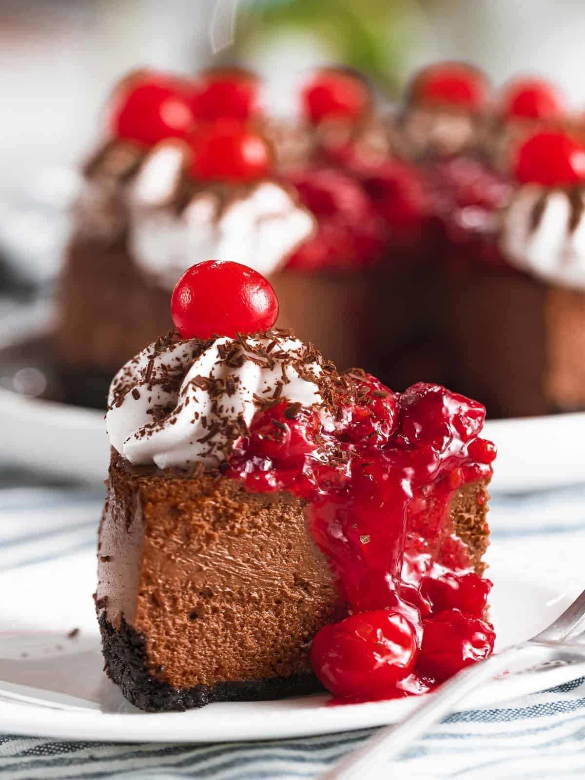 Black forest cheesecake with cherries, cherry topping, and whipped cream.