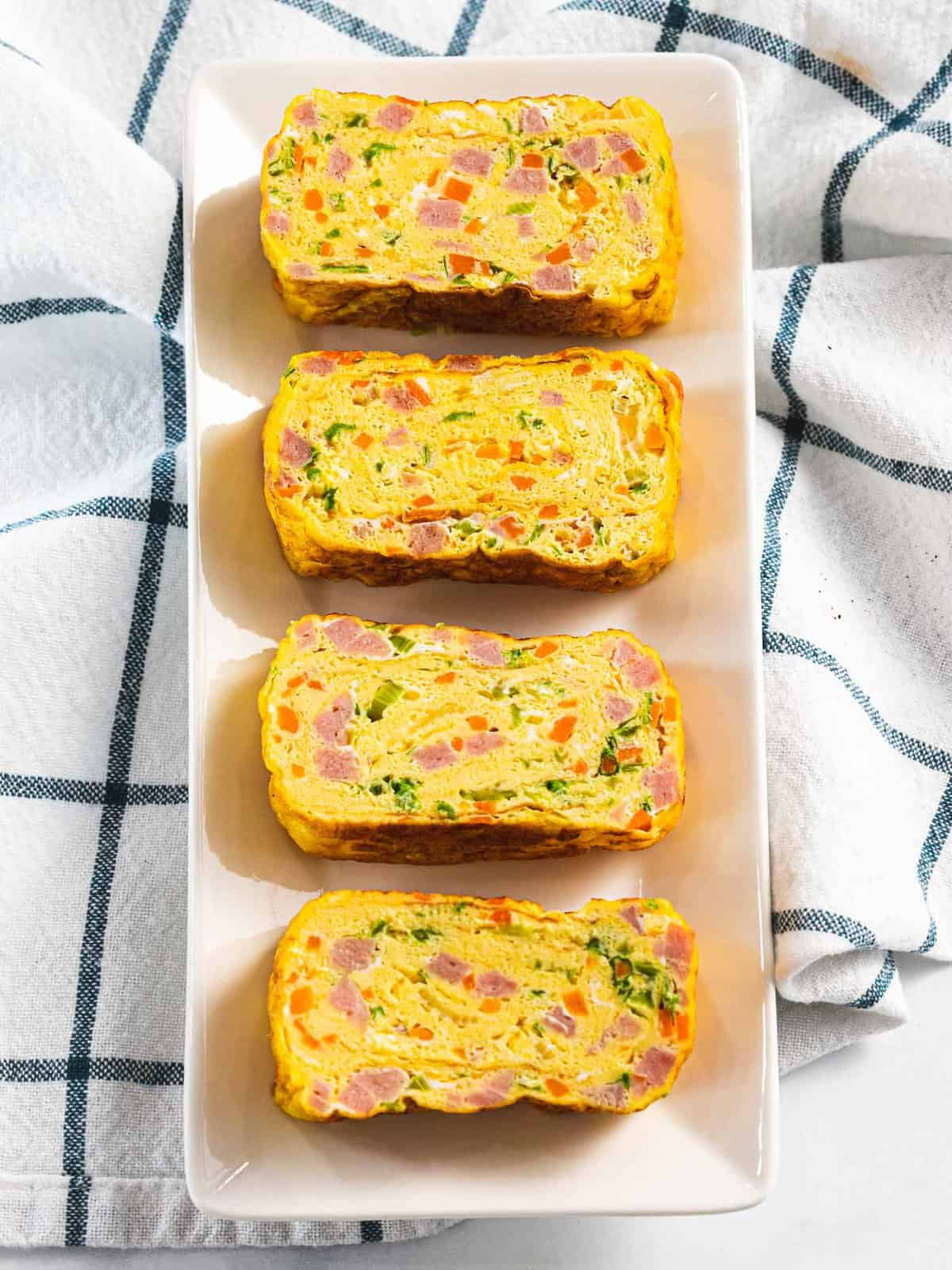 Korean rolled egg omelet or gyeran mari cut into pieces to show ham, carrots, and green onions.