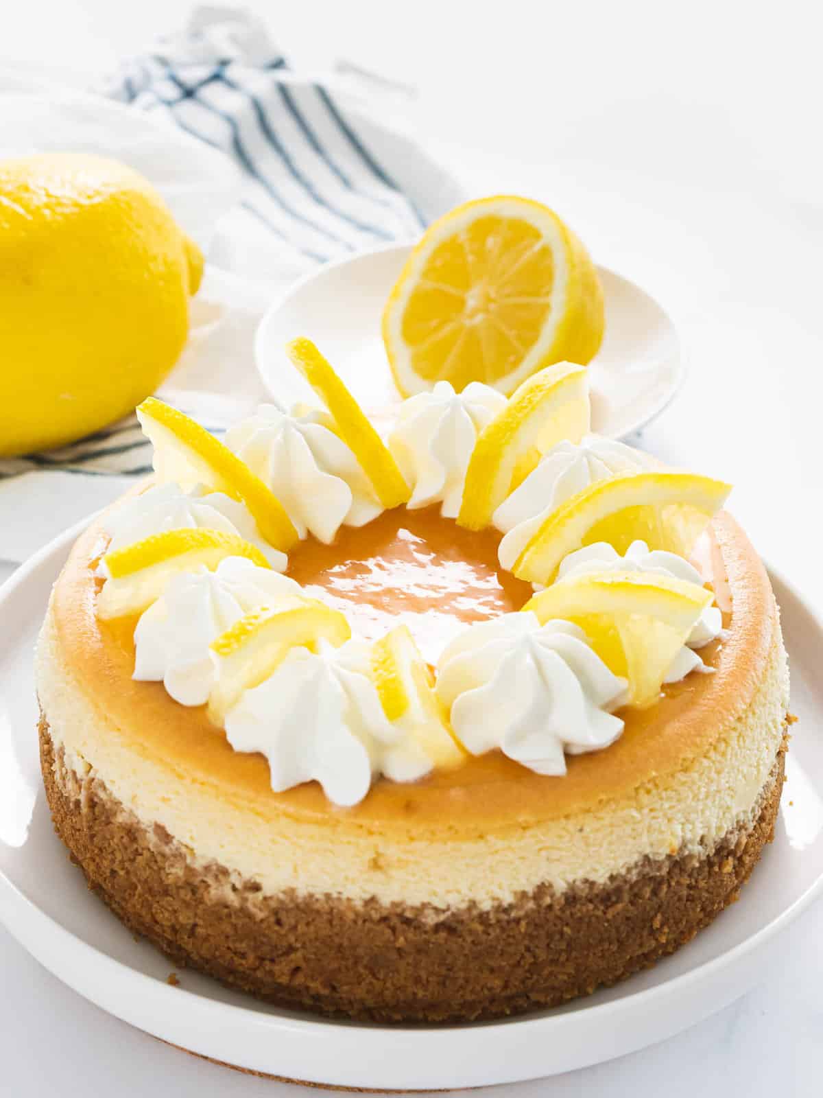 Lemon cheesecake with lemon slices, lemon curd, and whipped cream.