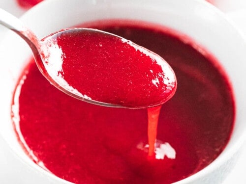 Raspberry sauce poured off a spoon.