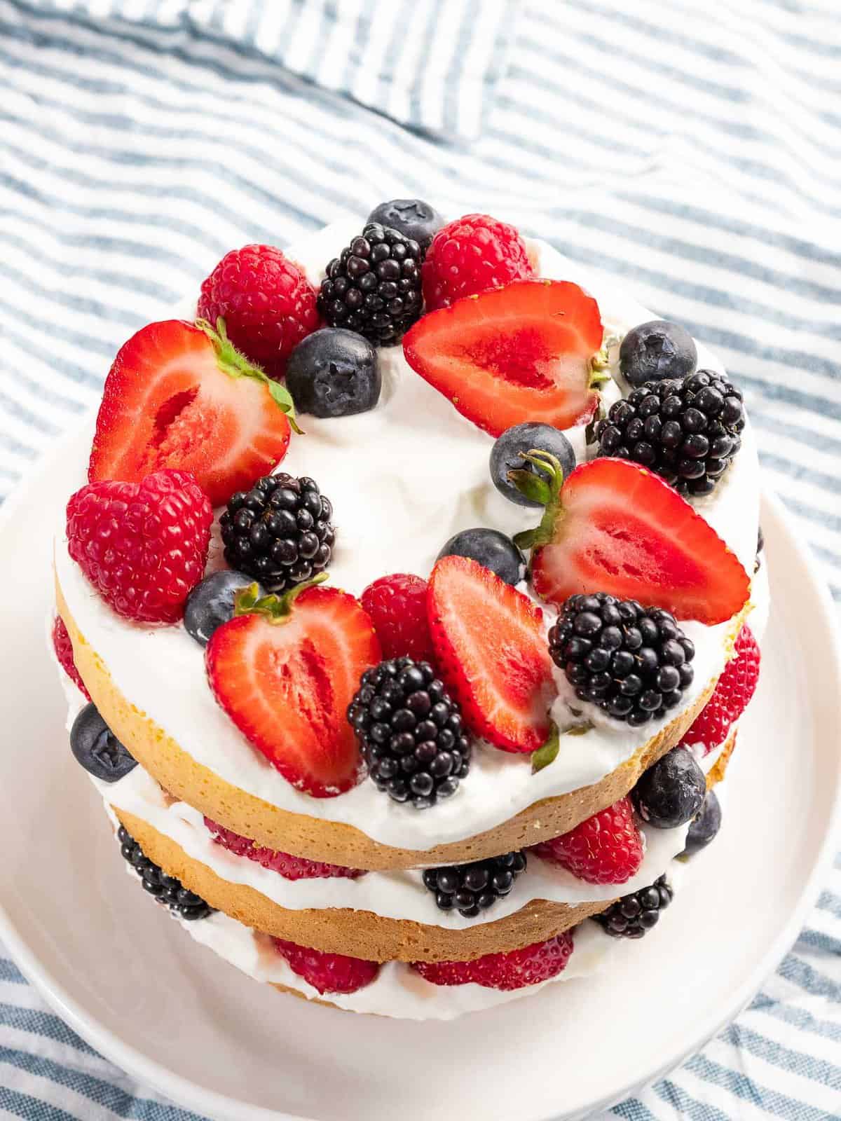 Berry cake with strawberries, blueberries, raspberries, and blackberries layered with cream and sponge cake.