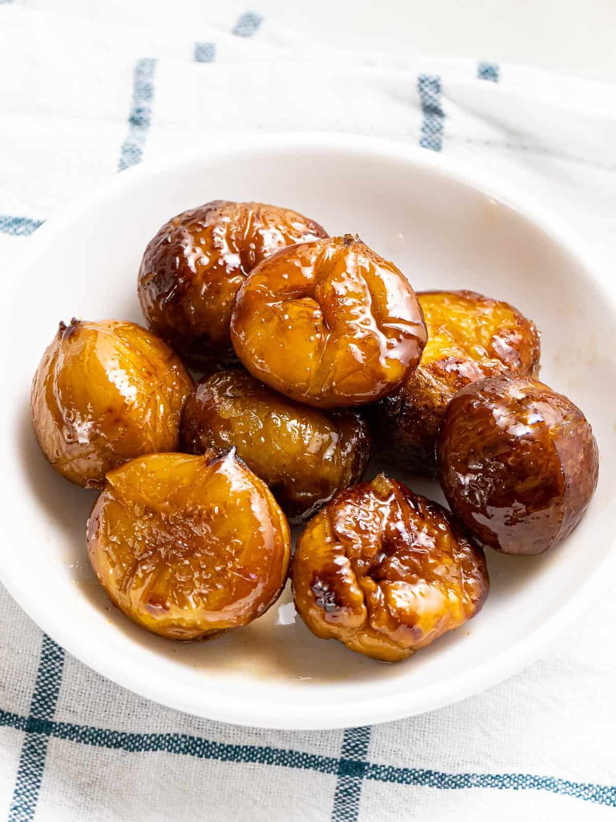 Quick candied chestnuts in spiced cinnamon sugar glaze in a white bowl.