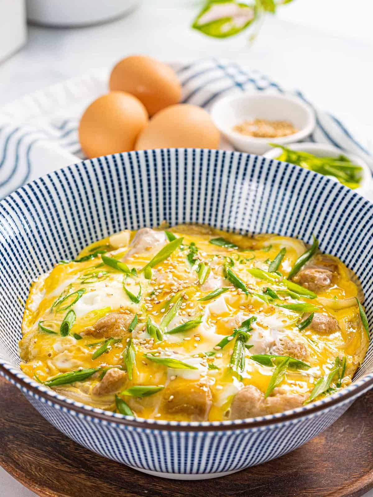 Oyakodon or Japanese chicken and egg rice bowl garnished with green onions.