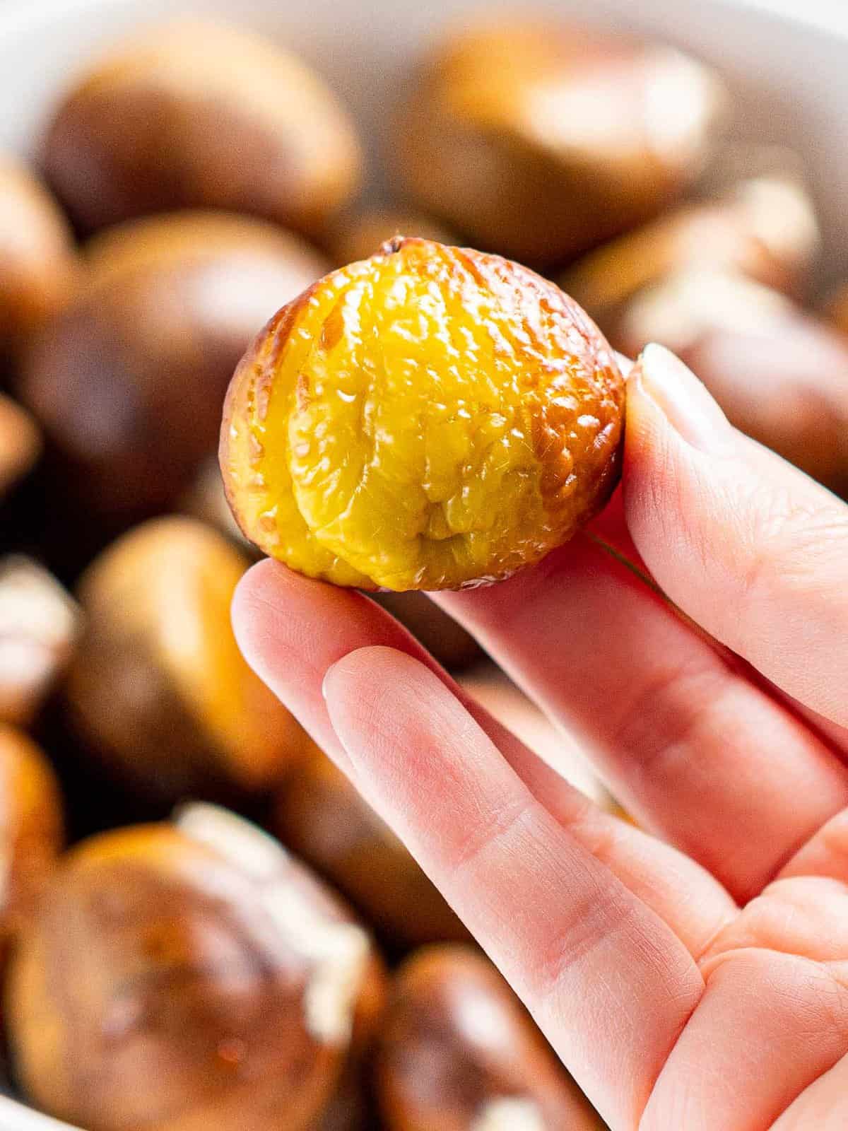 Peeled roasted chestnut held in hand.