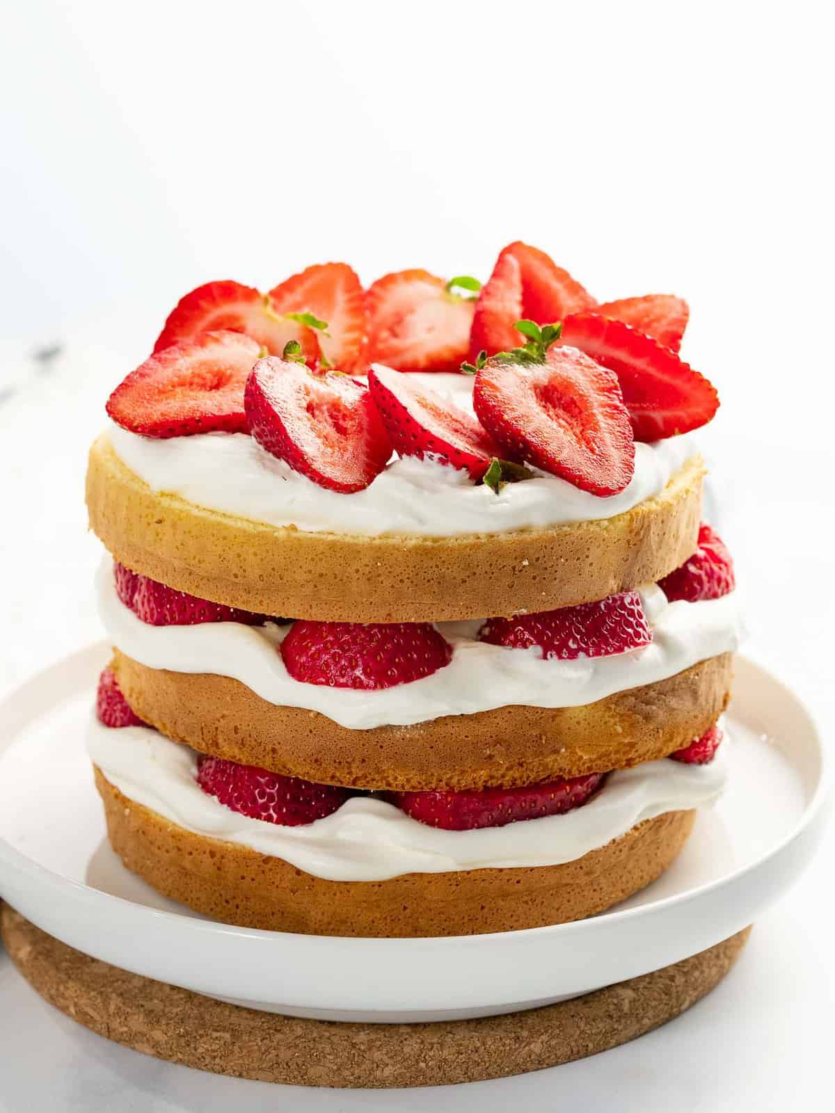Fresh strawberry cake with fresh strawberries, whipped cream, and layered cake.