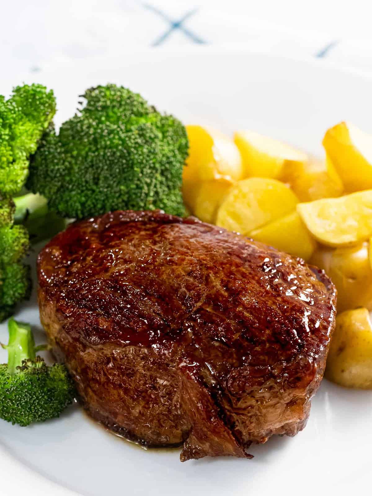 Reverse sear steak with a brown, crispy crust with broccoli and potatoes.