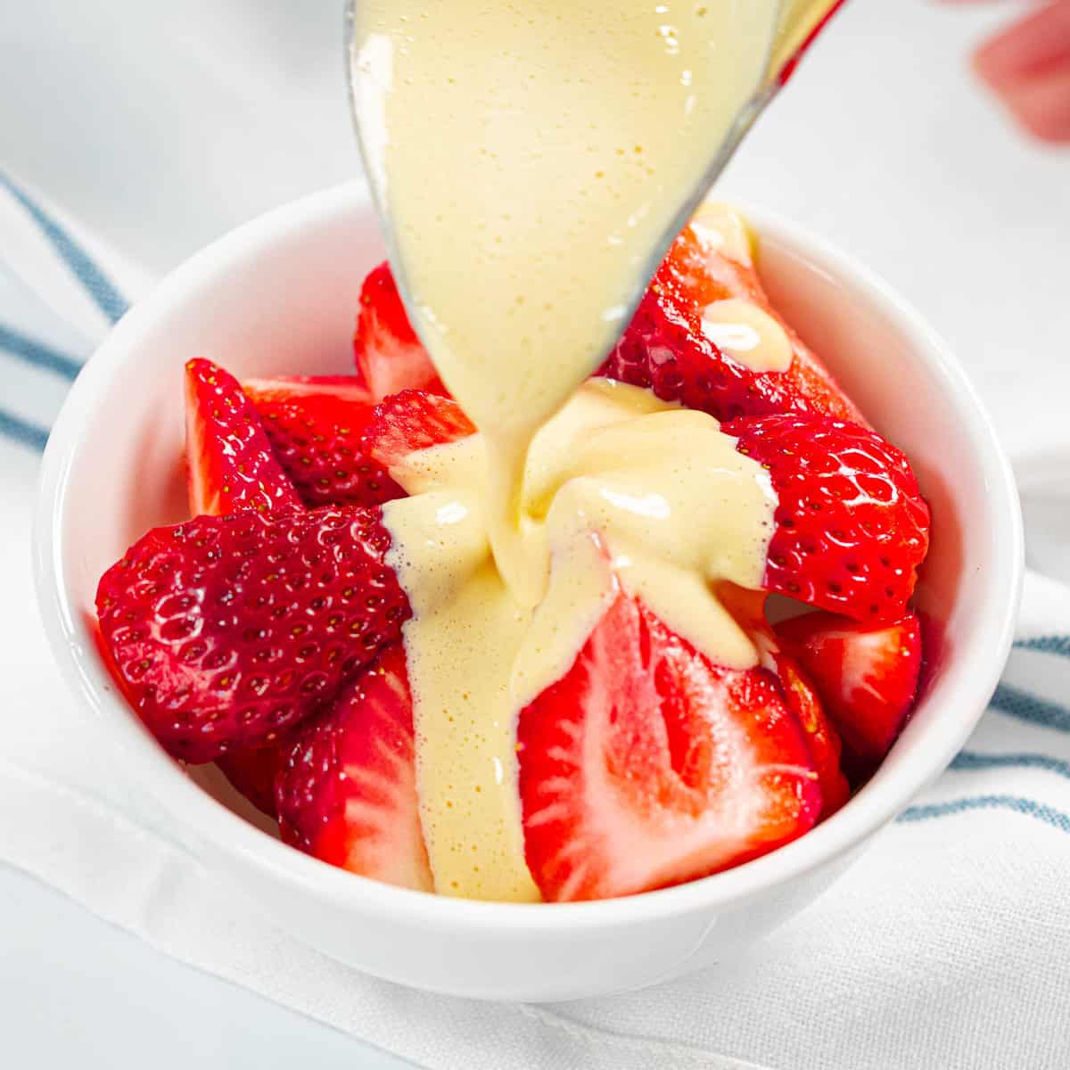 Zabaglione poured over a bowl of strawberries.