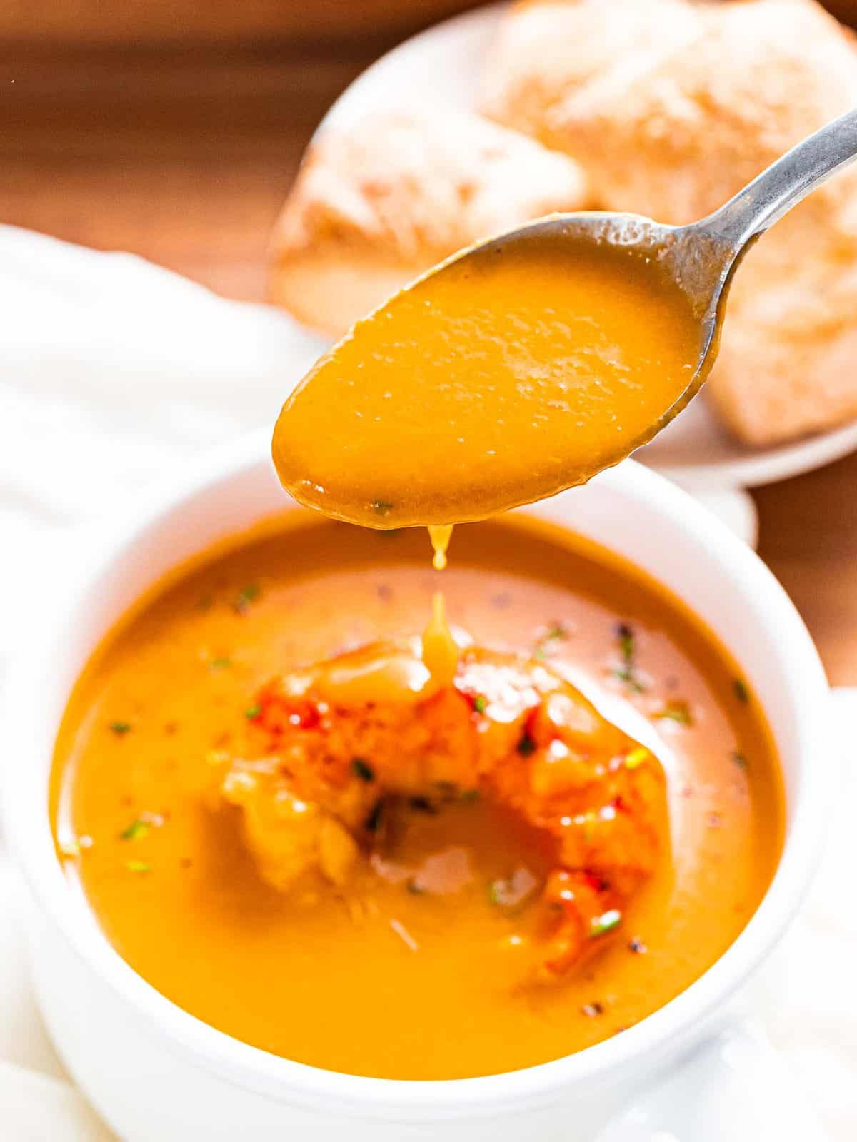 Smooth and creamy lobster bisque dripping off of a spoon.