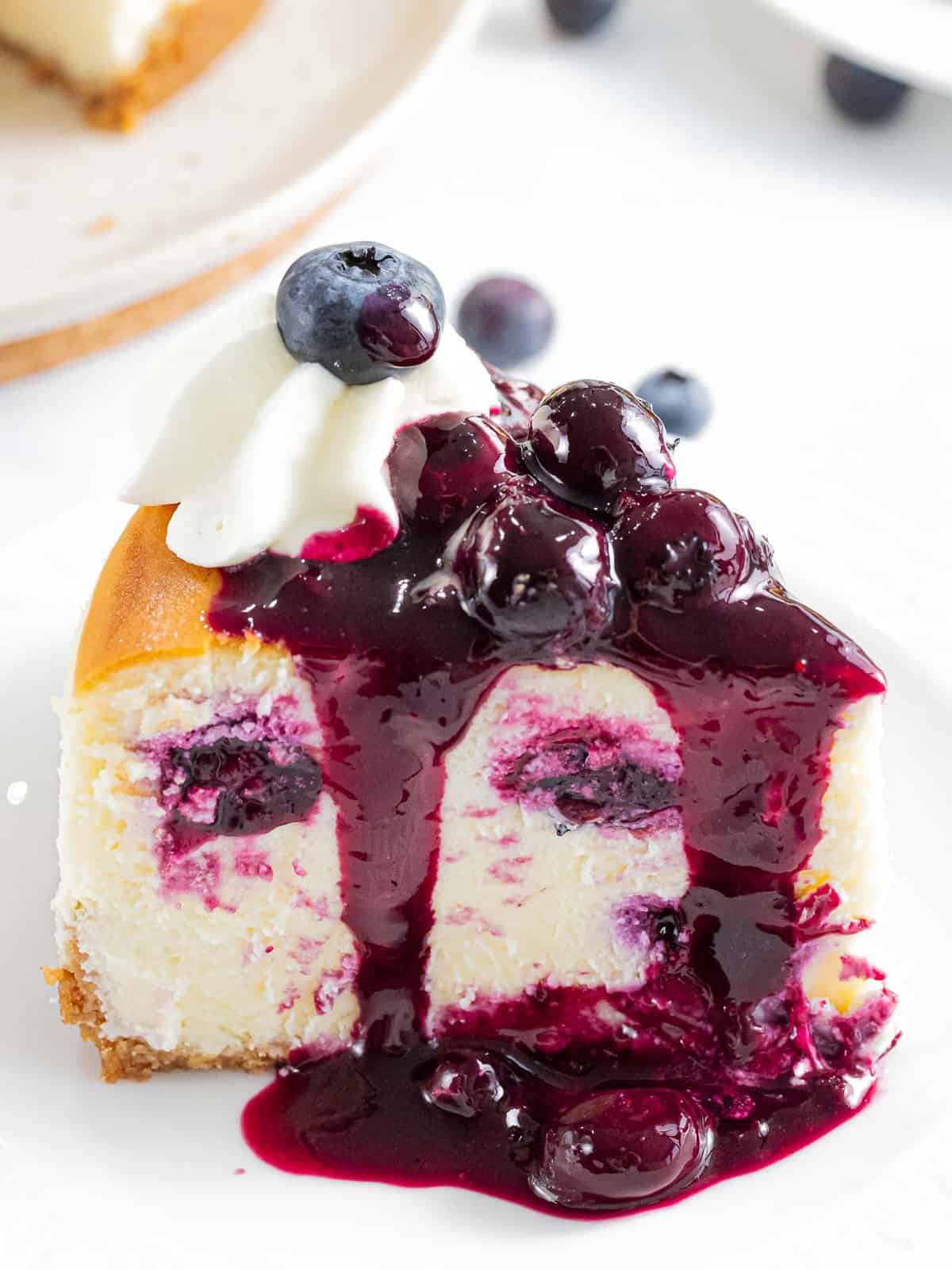 A slice of blueberry cheesecake made with fresh blueberries and topped with blueberry sauce.
