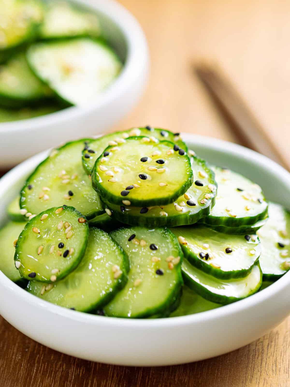 Sunomono or Japanese cucumber salad with sesame seeds in a white bowl.